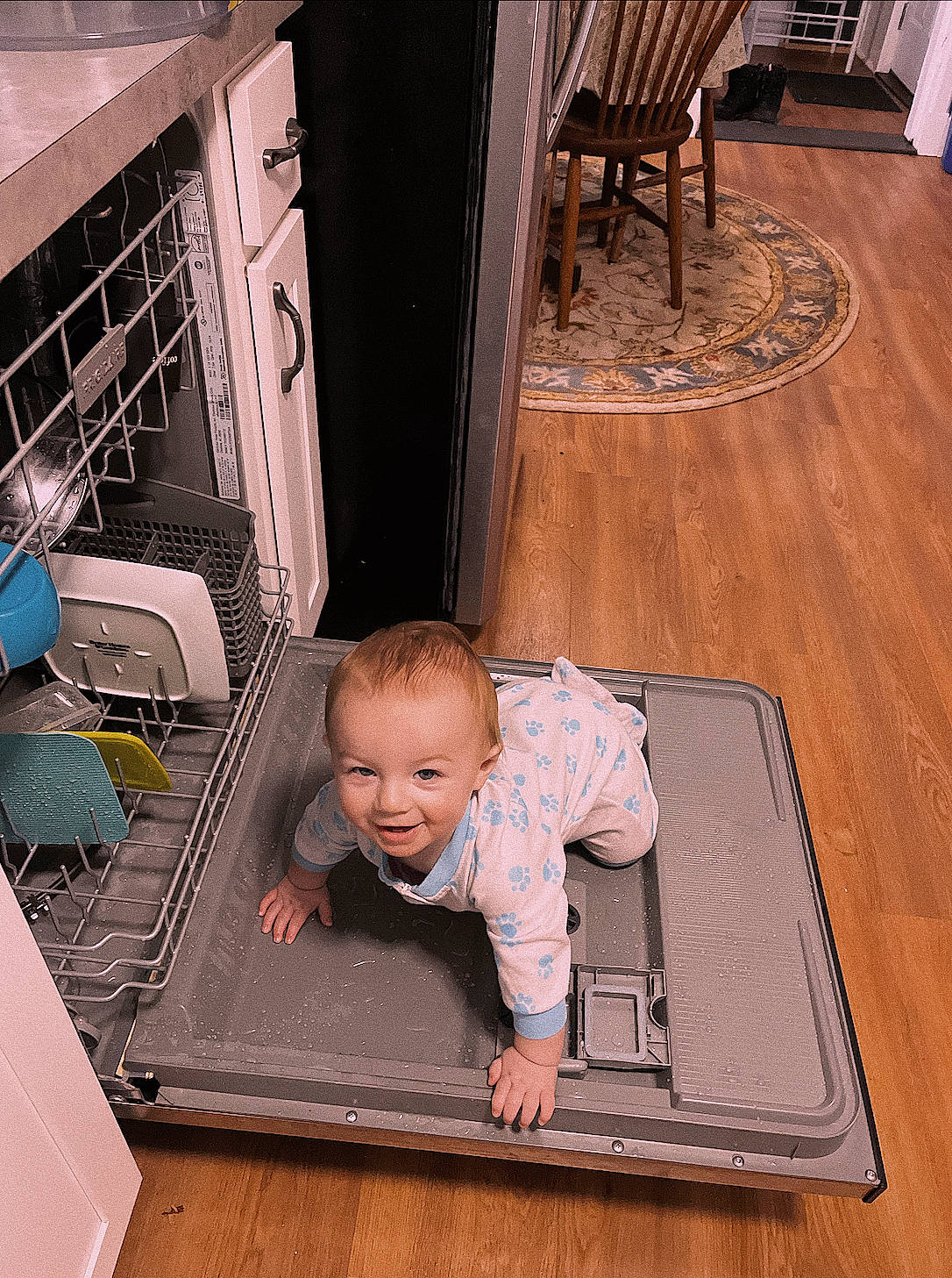 Atticus is registered to the contest to win money with this photo: baby, baby_toddler_clothing, brown, chair, child, comfort, floor, flooring, hardwood, person, rectangle, room, smile, t_shirt, table, toddler, varnish, white, wood, wood_flooring