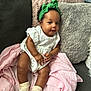 Khelani is registered to the contest to win money with this photo: baby, blanket, child, couch, cozy, curly_hair, cute, green, headband, home, indoor, infant, person, pillow, portrait, seated, smiling, socks, soft_texture, white_dress