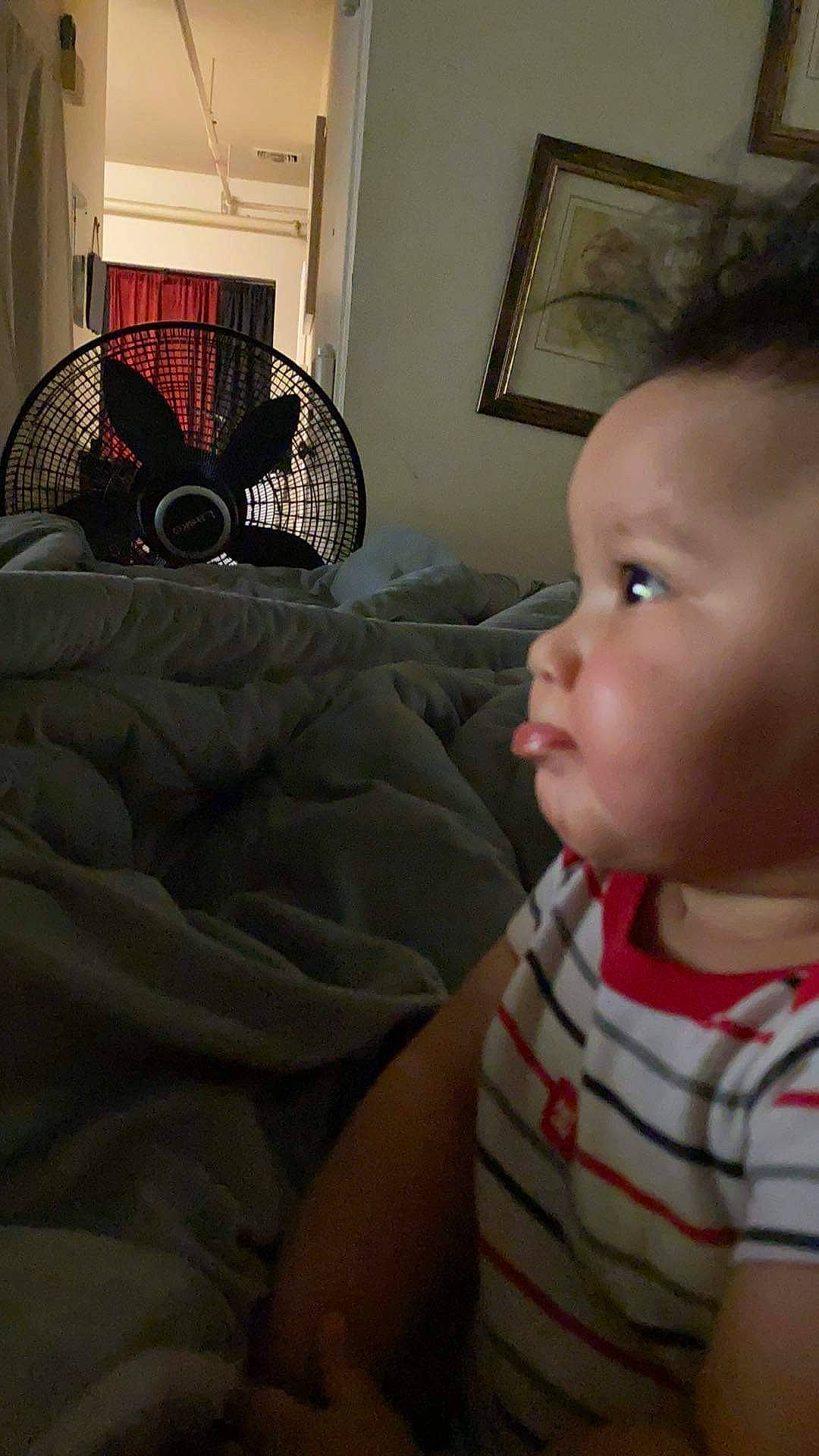 Cadence is registered to the contest to win money with this photo: baby, baby_toddler_clothing, chair, cheek, child, comfort, couch, floor, flooring, fun, iris, linens, living_room, nose, person, picture_frame, room, sitting, throw_pillow, toddler