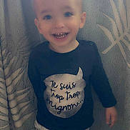 Naël participe au concours pour gagner de l'argent avec cette photo : toddler, child, smiling, standing, indoor, clothing, pants, shirt, blanket, pattern, face, happy, cute, young, person, portrait, light, hair, expression, cozy