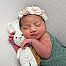 newborn, baby, sleeping, blanket, headband, flower, crocheted_bunny, toy, cuddle, peaceful, soft_texture, closeup, portrait, infant, resting, cute, hand, face, wrapped, cozy