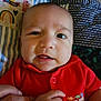 Amiri Lion is registered to the contest to win money with this photo: baby, infant, hand, red_shirt, dinosaur_print, quilt, colorful, close_up, face, expression, skin, person, child, cute, newborn, holding_hand, fabric, pattern, portrait, indoors