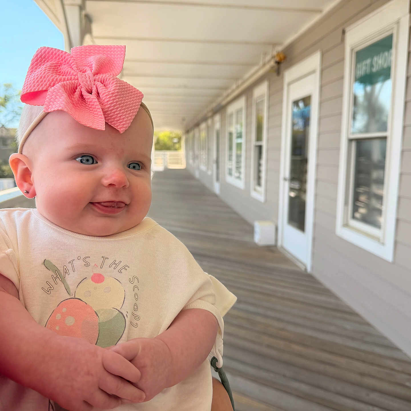 Kazelynn is registered to the contest to win money with this photo: baby, blue_eyes, child, cute, daylight, door, fruit_illustration, happy, headband, holding, infant, outdoor, person, pink_bow, porch, shirt, skin, smile, window, wooden_floor