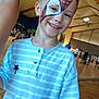 Menzo a rejoint le concours — aidez-le/la à gagner de superbes lots ! background, blue_shirt, boy, casual_clothing, ceiling_lights, child, event, face_paint, fun, group, gymnasium, happy, indoor, palm_tree_logo, people, portrait, short_hair, smile, striped_shirt, wooden_floor