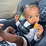 Autumn is registered to the contest to win money with this photo: toddler, child, car_seat, seatbelt, snack, food, hair_ties, white_shirt, shorts, curious, indoors, car_interior, safety, cute, face, legs, hands, eating, young_child, portrait