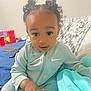 toddler, child, baby, person, face, curly_hair, pigtails, bed, blanket, clothing, indoor, expression, hand, blue, gray, nike, casual, young, looking, seated