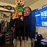 Chip is registered to the contest to win money with this photo: woman, dog, pet, indoor, smiling, braids, clothing, hoodie, casual, television, furniture, room, happy, portrait, holding, puppy, decor, wwe_belt, technology, home