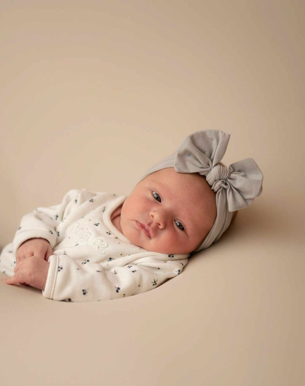 Kenza a rejoint le concours — aidez-le/la à gagner de superbes lots ! baby, infant, headband, bow, clothing, face, skin, lying_down, portrait, expression, newborn, soft_lighting, minimalistic, neutral_background, cute, child, indoors, peaceful, small_hands, resting