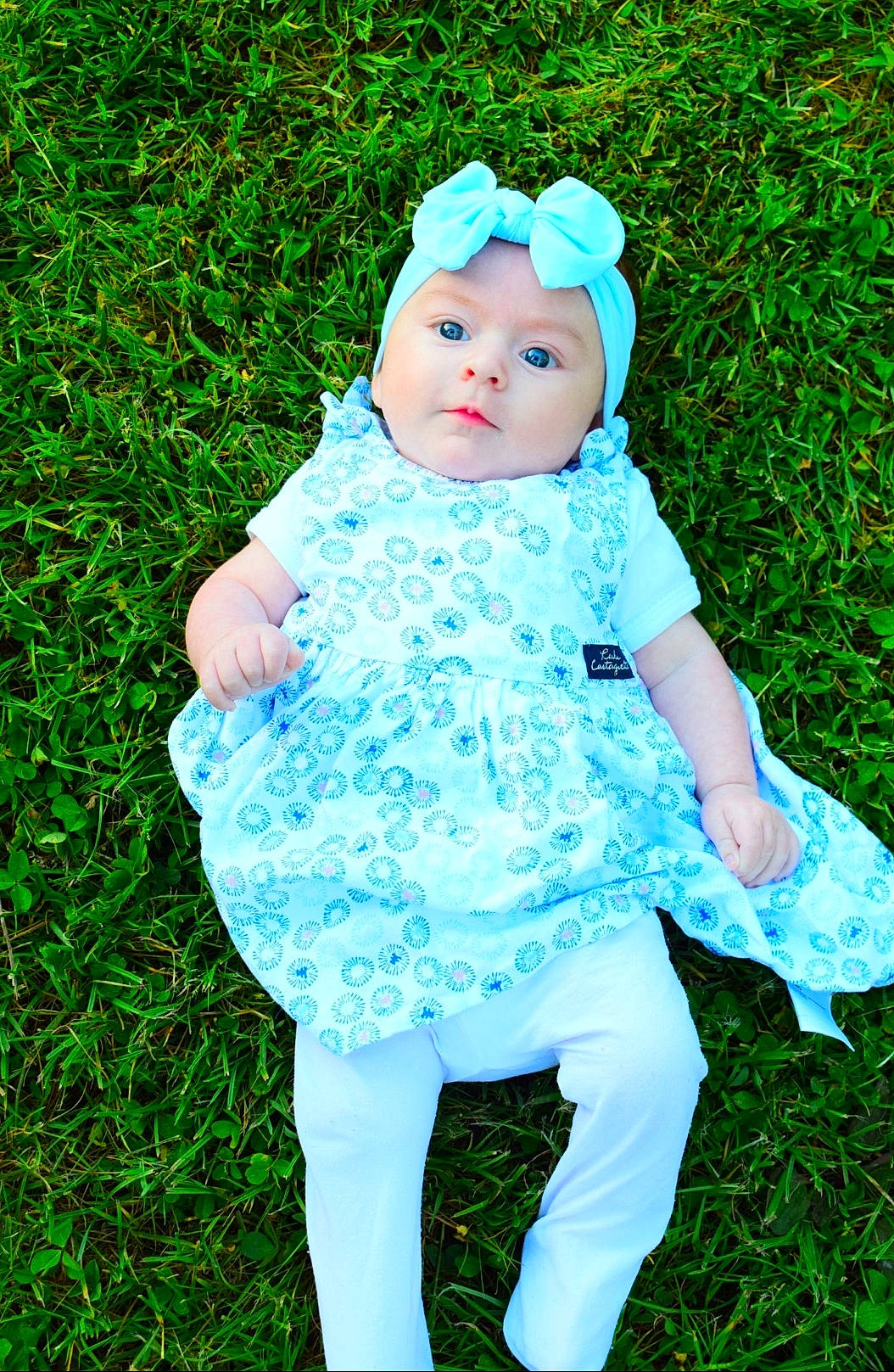 Mélona a rejoint le concours — aidez-le/la à gagner de superbes lots ! aqua, baby, baby_toddler_clothing, day_dress, doll, dress, electric_blue, event, fashion_accessory, grass, grassland, happy, headpiece, headwear, jewellery, leaf, pattern, people_in_nature, person, sitting