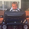 Mateo joined the competition — help win amazing prizes! toddler, child, toy_car, mercedes, amg, black, outdoor, deck, wooden_floor, steering_wheel, smiling, happy, sunlight, vehicle, playtime, cute, front_view, person, car, automobile