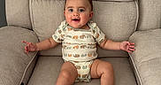 Jesse joined the competition — help win amazing prizes! baby, child, armchair, cushion, onesie, animal_print, smiling, happy, indoor, person, infant, cute, comfortable, seated, furniture, skin, face, legs, arms, expression