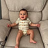 animal_print, armchair, arms, baby, child, comfortable, cushion, cute, expression, face, furniture, happy, indoor, infant, legs, onesie, person, seated, skin, smiling