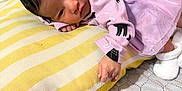 Cecilia is registered to the contest to win money with this photo: baby, infant, pillow, purple_dress, black_cat_print, lying_down, curious_expression, cushion, yellow_stripes, blanket, indoor, soft_lighting, newborn, cute, cozy, person, face, hand, footwear, home