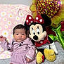 Cecilia is registered to the contest to win money with this photo: baby, infant, plush_toy, minnie_mouse, balloon, sunflower, blanket, purple_dress, diaper, patterned_bedspread, cute, indoors, child, soft_toy, toy, smiling, face, lying_down, decor, comfort