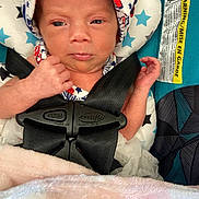 Zayla is registered to the contest to win money with this photo: baby, infant, car_seat, headwrap, blanket, straps, safety, child, newborn, face, person, clothing, seat, pout, cute, soft, pattern, star, indoors, closeup