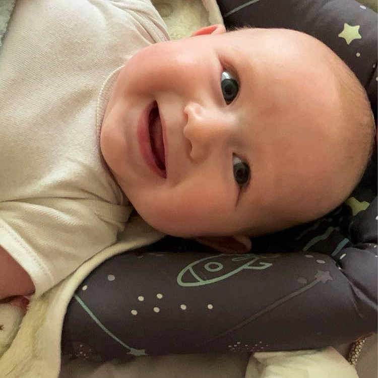 Odin is registered to the contest to win money with this photo: americanfootball, americanfootballball, baby, ball, clothing, cushion, face, football, furniture, happy, head, homedecor, laughing, newborn, person, photography, portrait, quilt, smile, sport