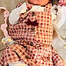 baby, infant, child, portrait, lying_down, checkered_outfit, pink_clothing, white_sleeves, bow, frills, blanket, bedding, toy, stuffed_toy, indoor, cozy, face, eyes_open, fashion, photography