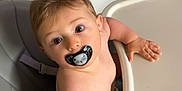 Hadriel a rejoint le concours — aidez-le/la à gagner de superbes lots ! baby, pacifier, high_chair, child, indoor, curious, reaching, kitchen, cabinet, paw_print, seatbelt, furniture, childhood, infant, person, cute, skin, hair, expression, table