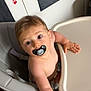 baby, pacifier, high_chair, child, indoor, curious, reaching, kitchen, cabinet, paw_print, seatbelt, furniture, childhood, infant, person, cute, skin, hair, expression, table