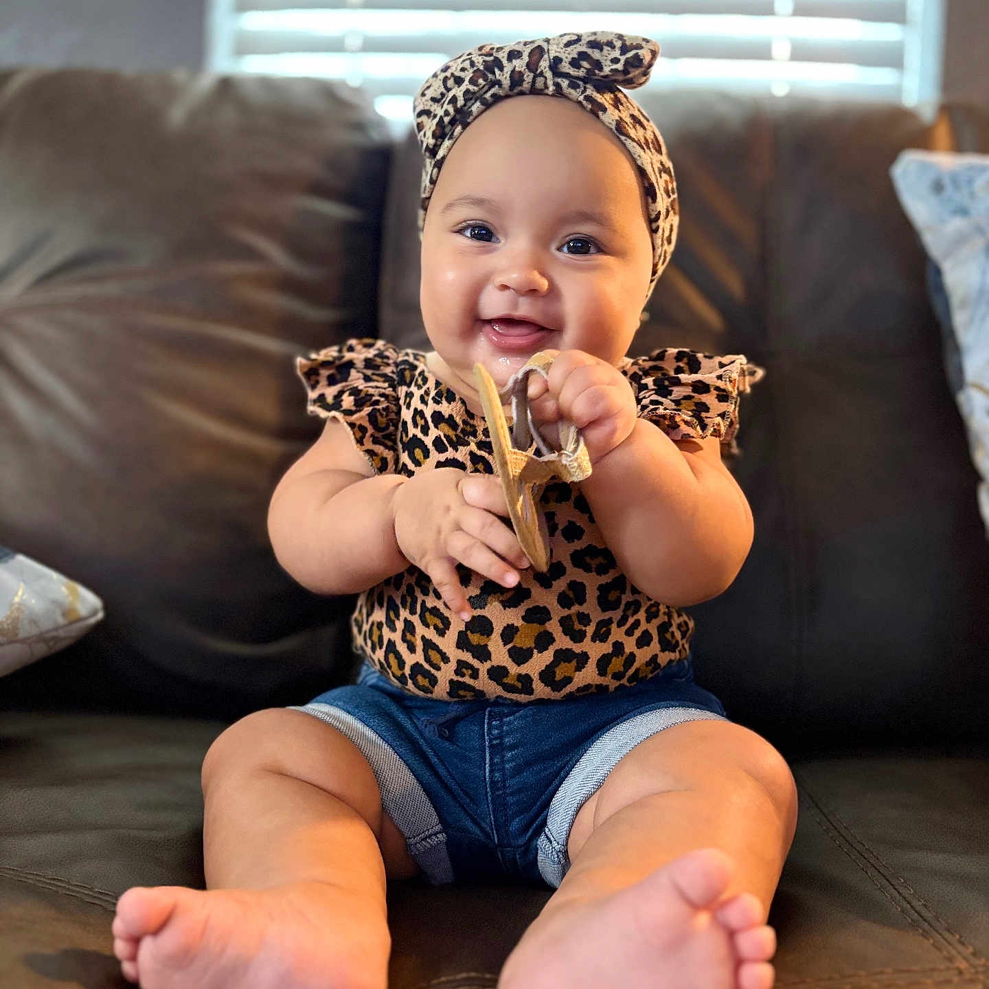 Denisse joined the competition — help win amazing prizes! baby, infant, smiling, leopard_print, headband, shorts, sandal, couch, indoor, child, cute, happy, feet, hands, sitting, portrait, window_blinds, home, comfort, clothing