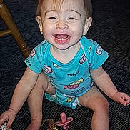 Ava joined the competition — help win amazing prizes! baby, blue_clothing, carpet, child, cute, expression, face, floor, foot, hand, happy, indoor, infant, onesie, pacifier, playful, sitting, small_child, smiling, toy