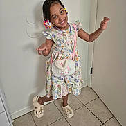 Zaillie joined the competition — help win amazing prizes! child, girl, smiling, portrait, standing, indoor, hallway, floral_dress, braided_hair, hair_beads, unicorn_purse, clogs, fashion, playful, posing, home, door, tile_floor, colorful, full_body