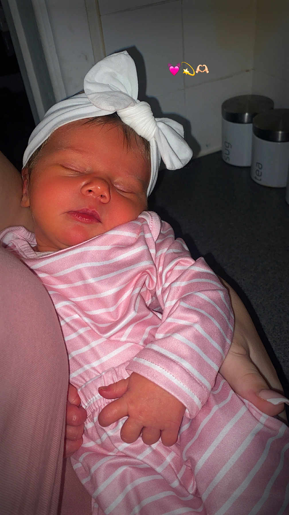 Lyla-Ann joined the competition — help win amazing prizes! baby, newborn, sleeping, pink_clothing, striped_clothing, headband, bow, hand, arm, indoor, kitchen, container, countertop, person, infant, cute, peaceful, soft_lighting, closeup, portrait