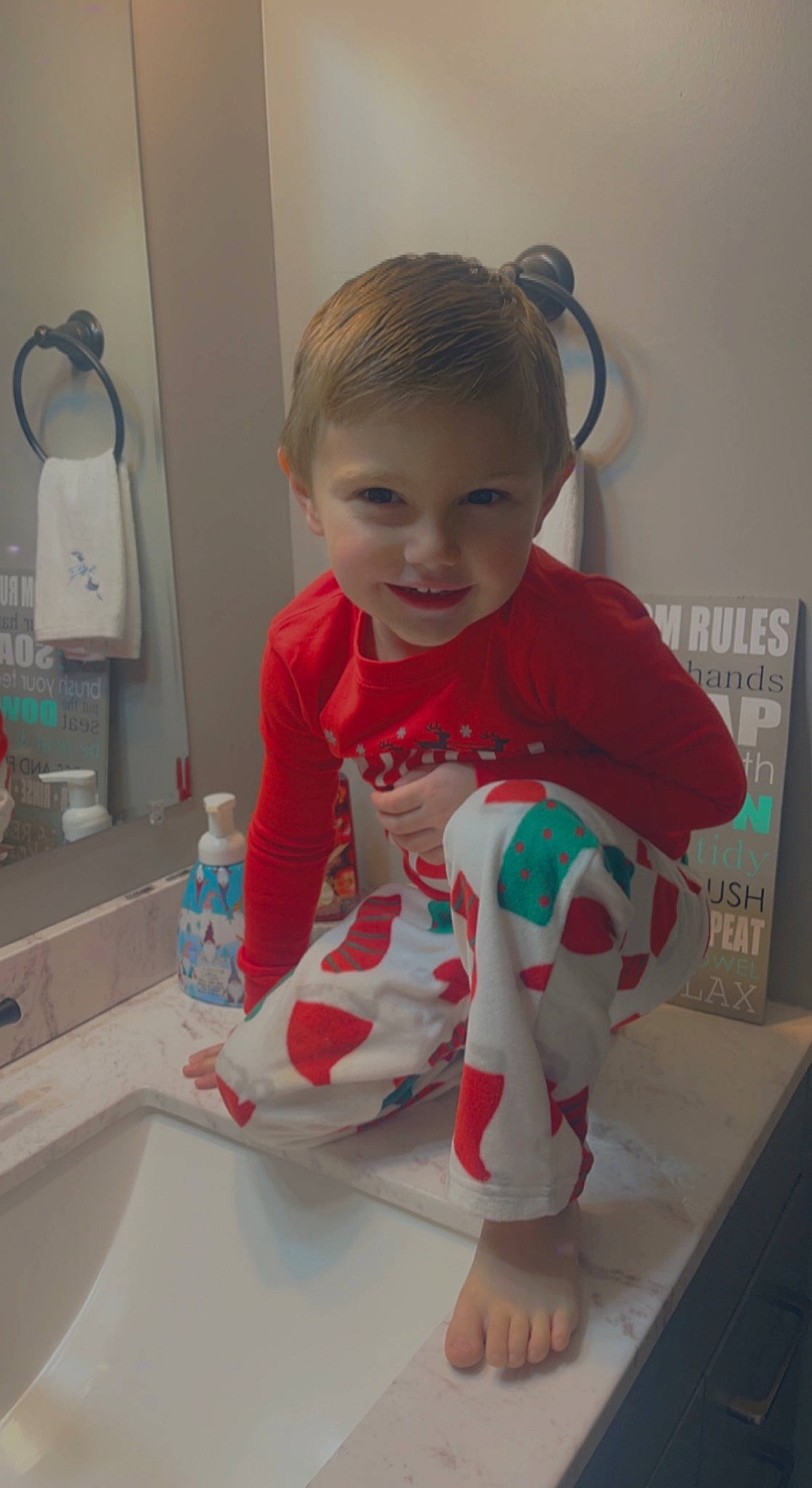 Logan is registered to the contest to win money with this photo: baby, baby_toddler_clothing, bathroom, carmine, child, foot, fun, joy, mirror, pattern, person, plumbing, plumbing_fixture, room, sink, sitting, sleeve, smile, t_shirt, tap