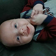 Easton joined the competition — help win amazing prizes! apparel, baby, blue_eyes, child, closeup, cute, face, grey_clothing, hand, happy, head, indoors, infant, lying_down, person, red_clothing, skin, smile, toddler, young