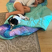 Belle is registered to the contest to win money with this photo: animal, blanket, carpet, child, comfort, cozy, curled_up, cute, floor, home, indoor, pet, playful, puppy, relaxation, resting, sleeping_bag, small_dog, white_clothing, young_child