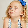 Brynlee is registered to the contest to win money with this photo: child, girl, blonde_hair, curly_hair, blue_bow, dress, floral_pattern, smile, playful, portrait, cute, young, cheeky, innocent, fashion, happy, person, face, head, studio