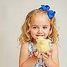 child, girl, blonde_hair, blue_bow, curly_hair, yellow_chick, animal, pet, holding, smiling, happy, cute, portrait, dress, blue_and_white, indoor, closeup, innocence, adorable, young