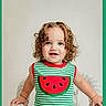 Raylynn joined the competition — help win amazing prizes! toddler, child, curly_hair, blue_eyes, striped_shirt, watermelon_applique, tank_top, white_wicker_chair, indoor, portrait, smiling, happy, cute, person, young_child, standing, framed_photo, green_border, fashion, casual_clothing