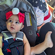 Blake joined the competition — help win amazing prizes! baby, car_seat, red_bow, headband, pompon, child, car_interior, seatbelt, straps, person, leg, hand, clothing, adult, driver, beard, star_pattern, blue, red, white