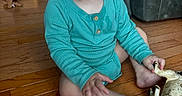 James is registered to the contest to win money with this photo: toddler, child, baby, floor, wooden_floor, toy, toy_horse, onesie, clothing, living_room, couch, table, furniture, happy, smiling, sitting, indoor, person, skin, hand