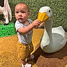 James joined the competition — help win amazing prizes! toddler, child, statue, duck, toy, indoor, curious, shorts, white_crocs, green_background, cow_statue, play_area, yellow_floor, baby, person, cute, exploring, hand, face, standing