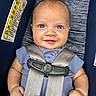 baby, child, car_seat, blue_shirt, smile, face, infant, seatbelt, safety, happy, closeup, human, skin, cute, young, portrait, clothing, seat, hands, indoor