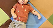 Levi is registered to the contest to win money with this photo: baby, baby_face, barefoot, cactus_shirt, casual_clothing, child, colorful_mat, cute, floor_mat, gray_pants, happy, indoor, infant, lying_down, one_child, orange_shirt, playmat, playtime, smiling, young_child