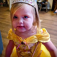 Lilah is registered to the contest to win money with this photo: child, girl, princess_costume, tiara, yellow_dress, indoor, wooden_floor, face, blonde_hair, portrait, costume, young_child, smiling, curious, closeup, person, celebration, party, dress_up, happy
