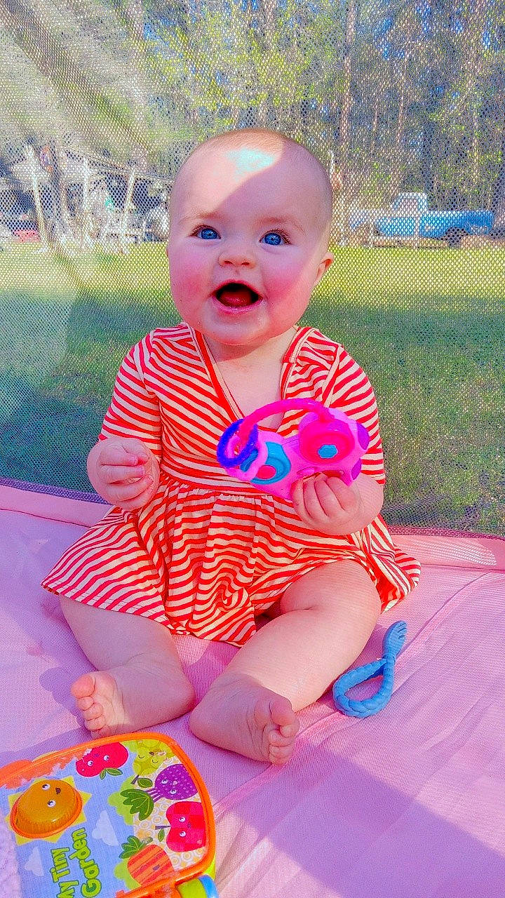 Lilah joined the competition — help win amazing prizes! baby, baby_toddler_clothing, cheek, child, dress, electric_blue, fun, grass, happy, leisure, magenta, pattern, person, pink, plant, sitting, skin, sleeve, smile, summer