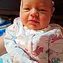 Lucy is registered to the contest to win money with this photo: baby, infant, child, face, onesie, animal_print, hand, clothing, cute, portrait, skin, eyes, mouth, cheeks, newborn, expression, indoor, person, soft, closeup