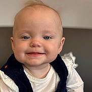 Jack joined the competition — help win amazing prizes! baby, bib, blond_hair, blue_eyes, child, close_up, clothing, couch, dark_vest, eyes, face, happy, indoors, infant, photography, portrait, sitting, smiling, soft_lighting, white_shirt
