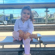 Angelyna a rejoint le concours — aidez-le/la à gagner de superbes lots ! bench, blouse, bus, child, clothing, face, female, footwear, furniture, girl, head, outdoors, pants, person, photography, portrait, shorts, sitting, transportation, vehicle