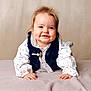 baby, child, smiling, blue_eyes, dimples, white_clothing, navy_vest, blanket, soft_texture, portrait, cute, happy, infant, crawling, indoor, face, hands, light_background, young_child, studio_photo