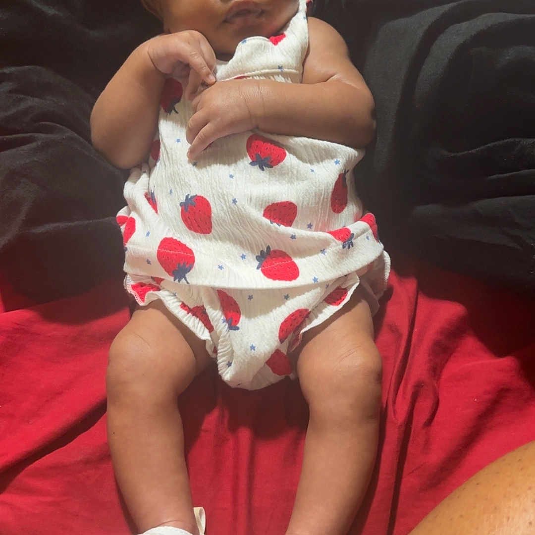 Amirracle Thompson is registered to the contest to win money with this photo: baby, baby_girl, black_blanket, blanket, child, clothing, cute, feet, headband, indoors, infant, legs, person, portrait, red_blanket, relaxing, strawberry_print, toddler, toes, white_sandals
