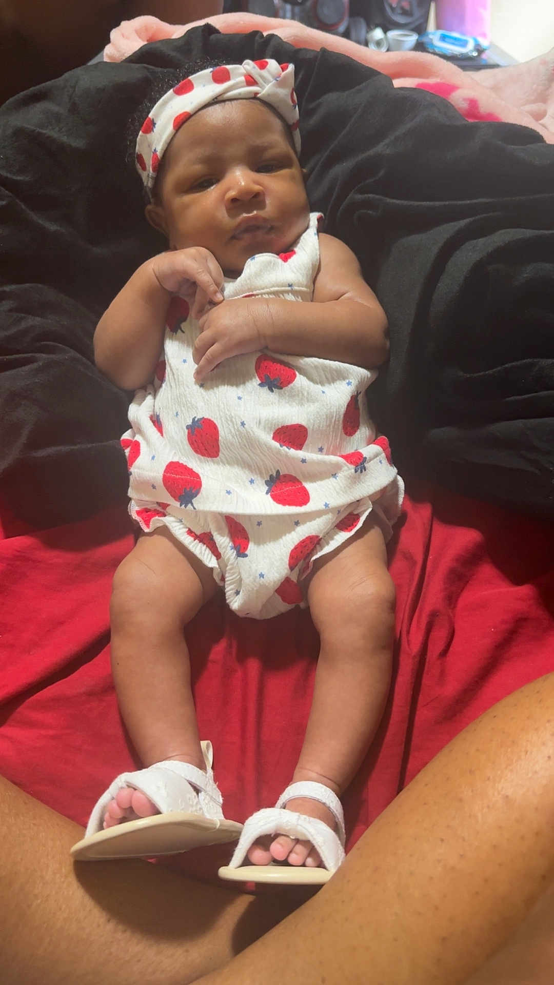 Amirracle Thompson is registered to the contest to win money with this photo: baby, infant, child, headband, strawberry_print, white_sandals, blanket, red_blanket, black_blanket, legs, feet, toes, clothing, relaxing, indoors, person, cute, portrait, baby_girl, toddler