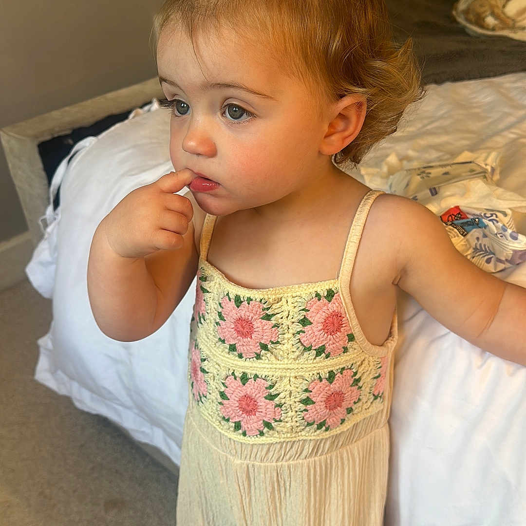 Milah-Bleu is registered to the contest to win money with this photo: bed, bedroom, carpet, child, clothing, curious, curly_hair, cute, expression, face, finger_in_mouth, floral_top, indoor, pants, person, ponytail, skin, standing, toddler, young_child