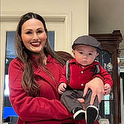 Ezekiel joined the competition — help win amazing prizes! woman, baby, indoor, red_clothing, smile, serious, hat, suspenders, cabinet, furniture, portrait, holding, person, child, family, home, long_hair, fashion, happy, casual