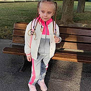 Lyana participe au concours pour gagner de l'argent avec cette photo : child, braids, park, bench, outdoor, grass, tree, sidewalk, jacket, tracksuit, sneakers, daylight, young, person, casual_clothing, nature, quiet, standing, shoes, portrait