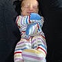 baby, infant, sleeping, onesie, striped_clothing, feet, legs, black_pants, cozy, indoor, person, closeup, cute, peaceful, newborn, child, resting, soft_lighting, casual, home